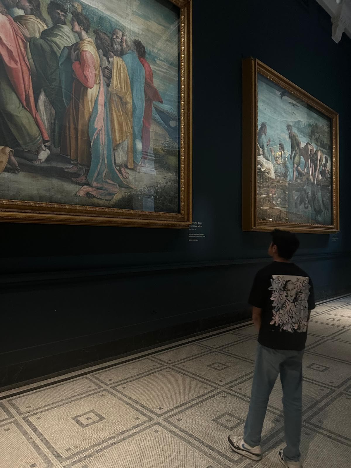 A visitor taking in large paintings in an art gallery