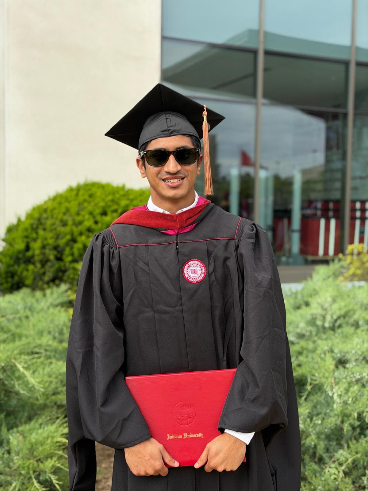 Atharva in graduation robes holding an Indiana University diploma cover